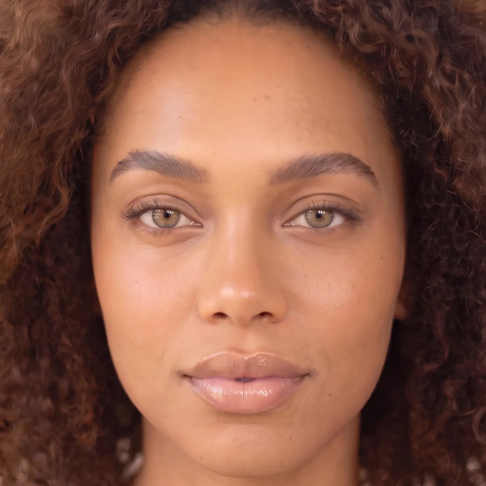 Model with deep skin tone, bare lashes, before applying SKYRA natural magnetic lashes