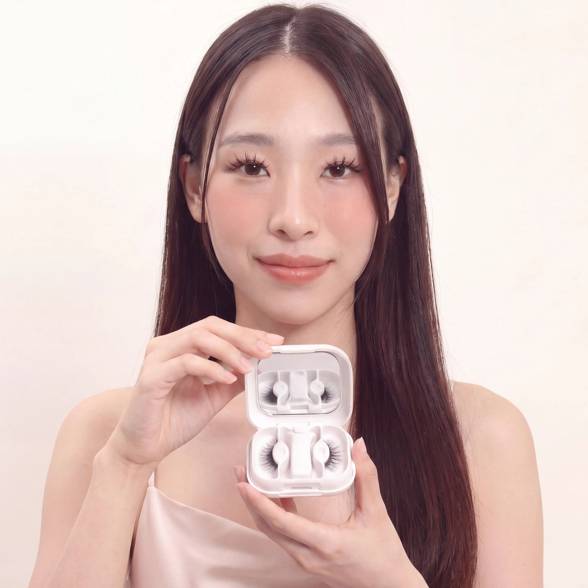 Beautiful asian model holding an open Skyra Beauty magnetic eyelash case, showcasing reusable magnetic lashes and applicator